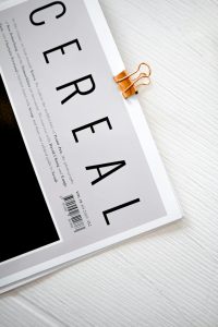 Stylish magazine cover featuring a bold CEREAL title clipped with a gold binder on white background.