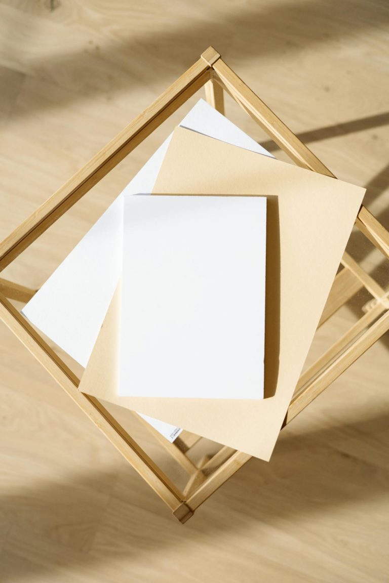 Stylish minimalist design featuring stacked papers on a wooden table, ideal for mockups and design presentations.